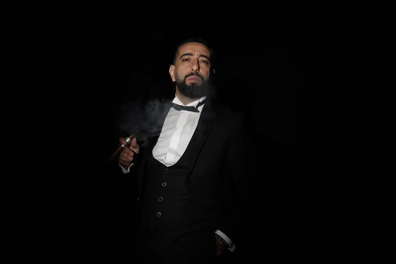 Siyah fon önünde, duman arasında ayakta duran Nursamet Yardımedici